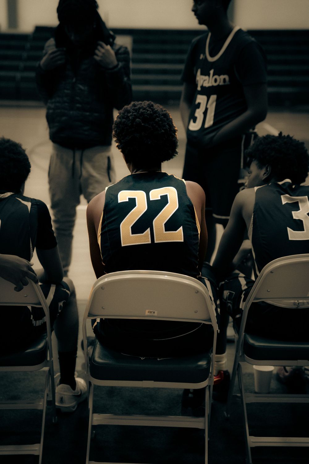 Avalon basketball player #22 sits on bench chair during game.