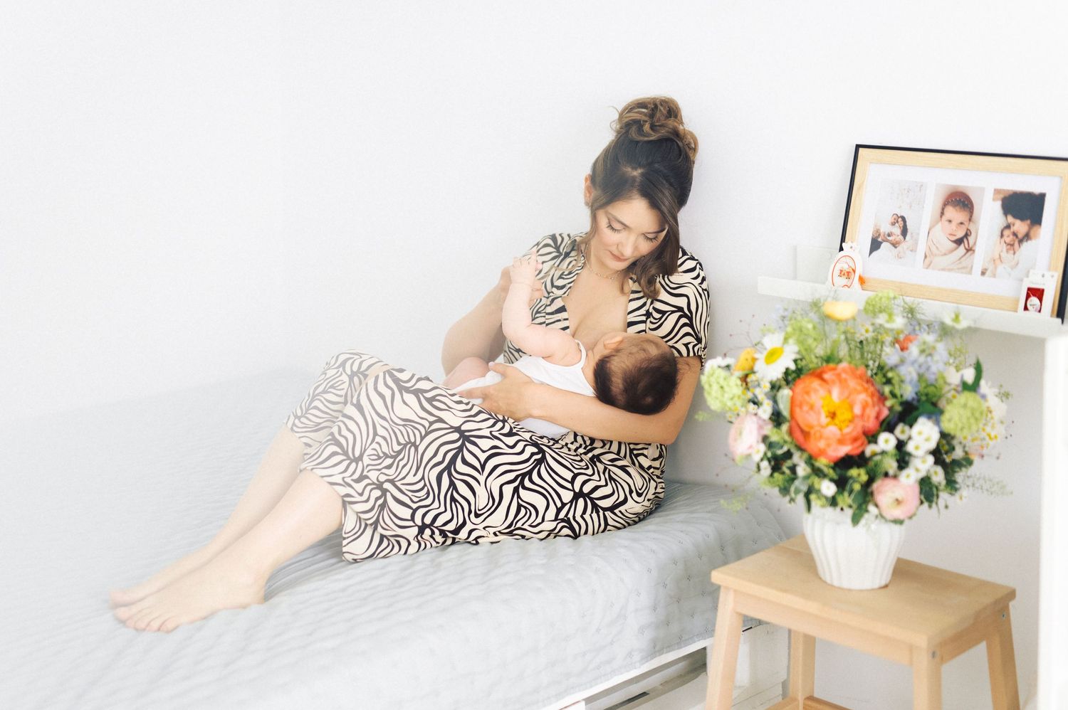 Person in zebra print dress relaxes on gray couch next to side table with colorful floral arrangement.
