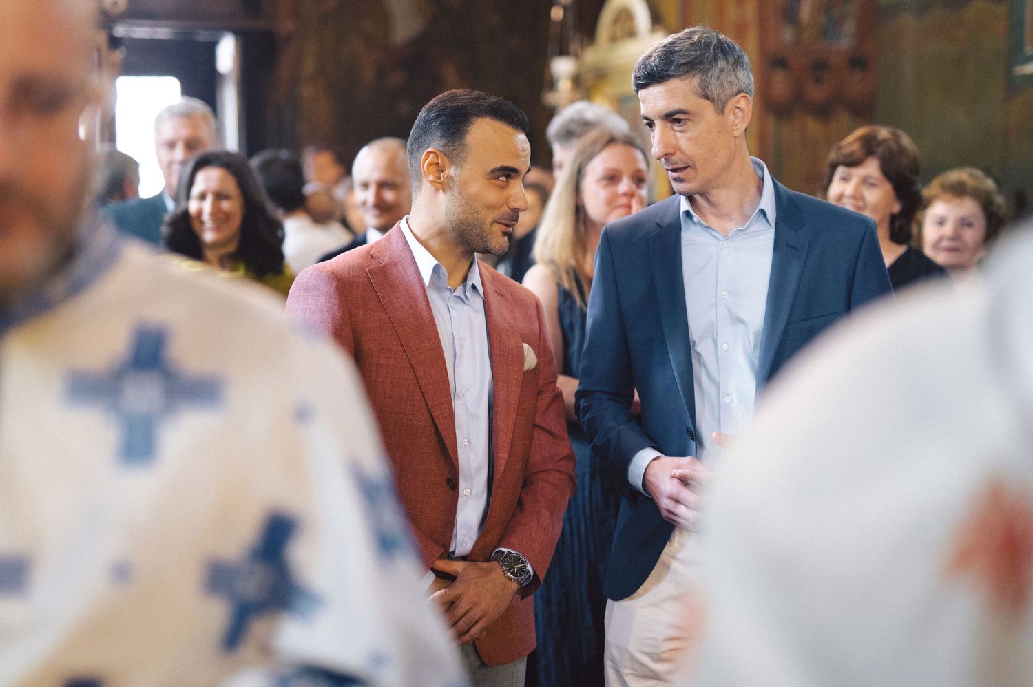 Two people in formal attire standing together at what appears to be an indoor social gathering or event.