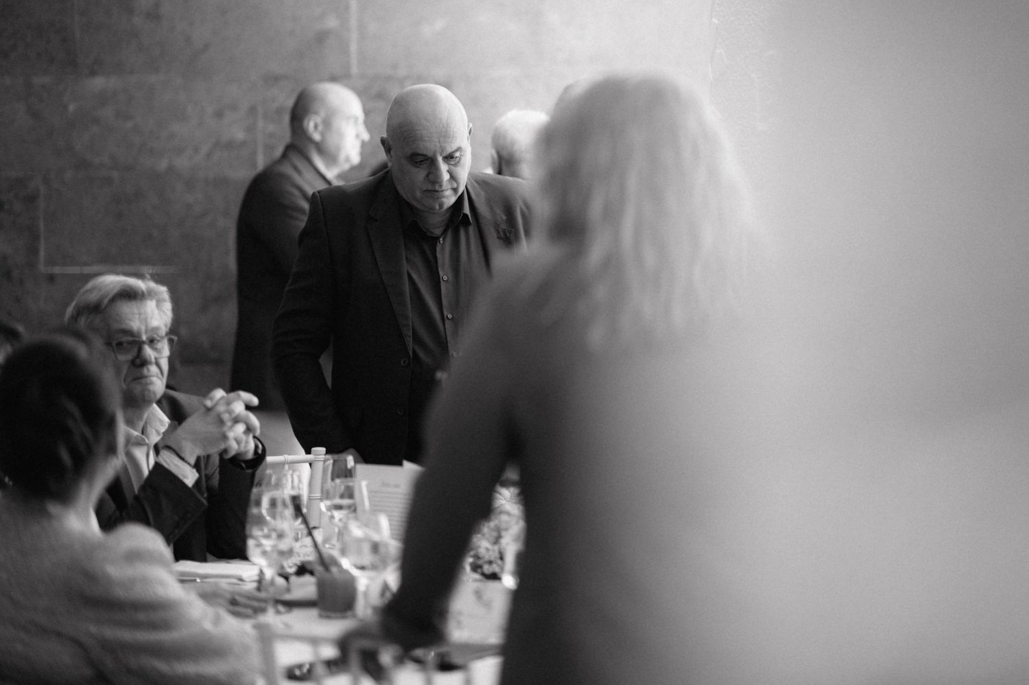Black and white candid shot of guests engaged in conversation during a formal gathering.