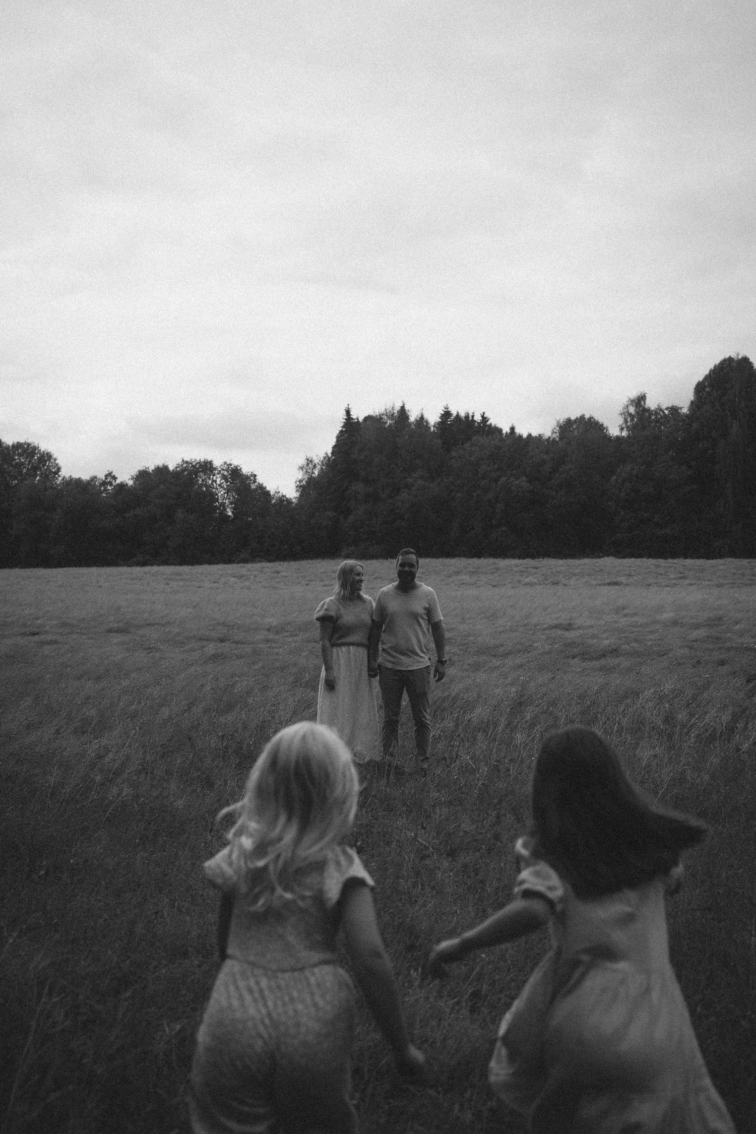 Black and white photo of people walking together through a grassy meadow at dusk.