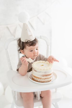 Bébé découvrant du bout des doigts son gâteau de premier anniversaire dans un décor fine art au studio de Judith Trudel près de Québec