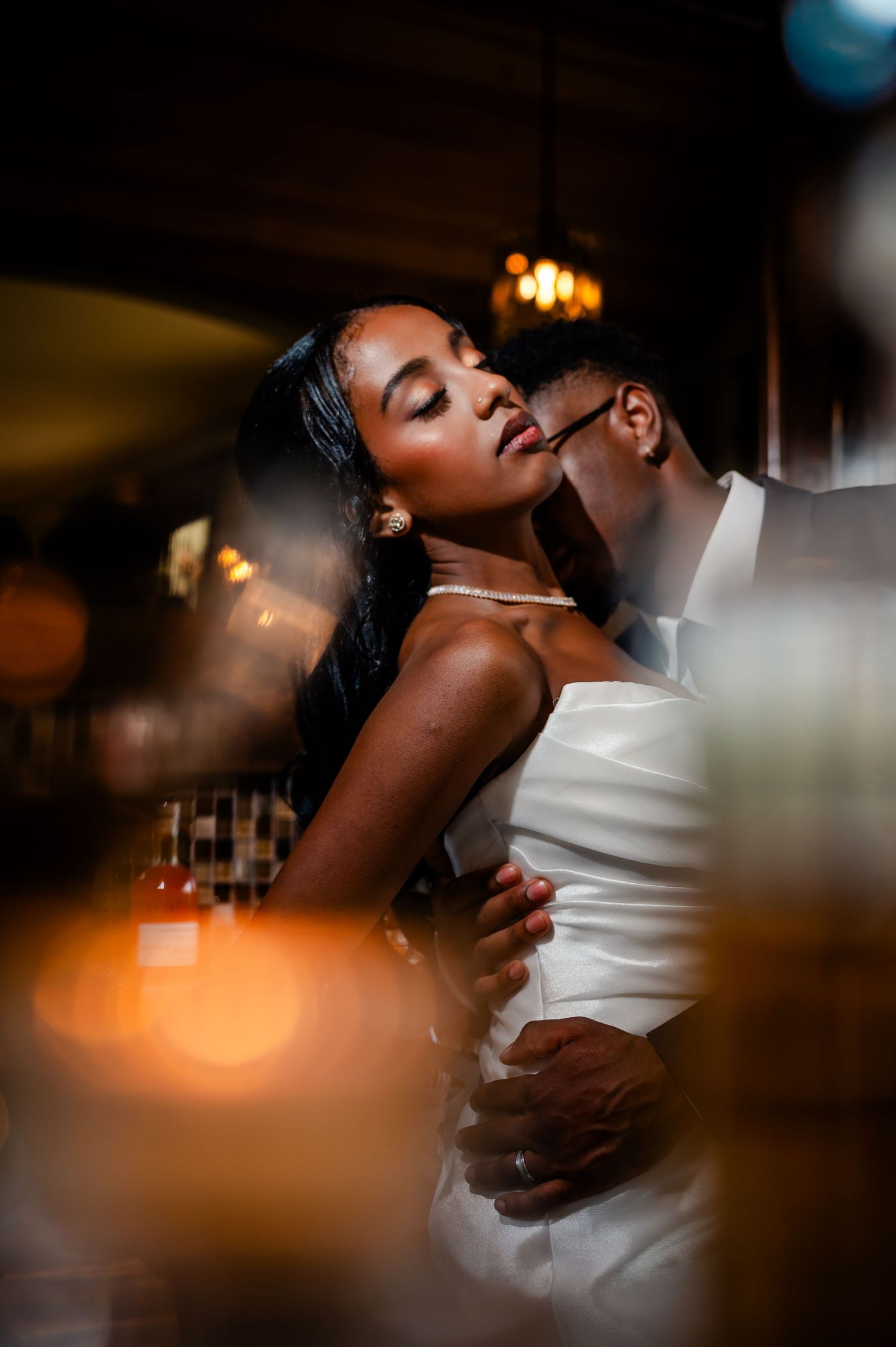 A person wearing white clothing is photographed in an intimate candid moment with warm lighting and blurred background.
