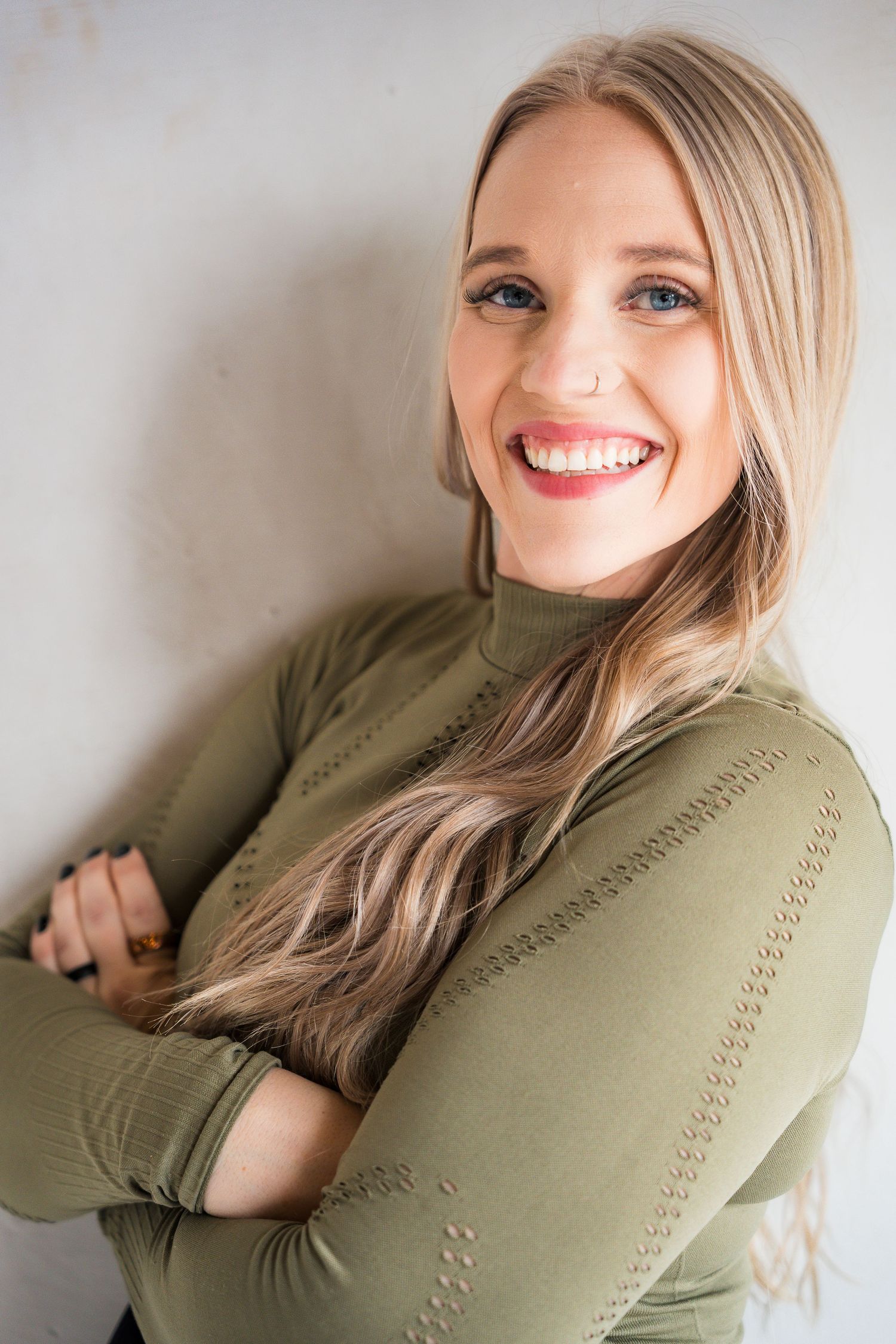 Casual poses in olive green sweater against neutral studio background.