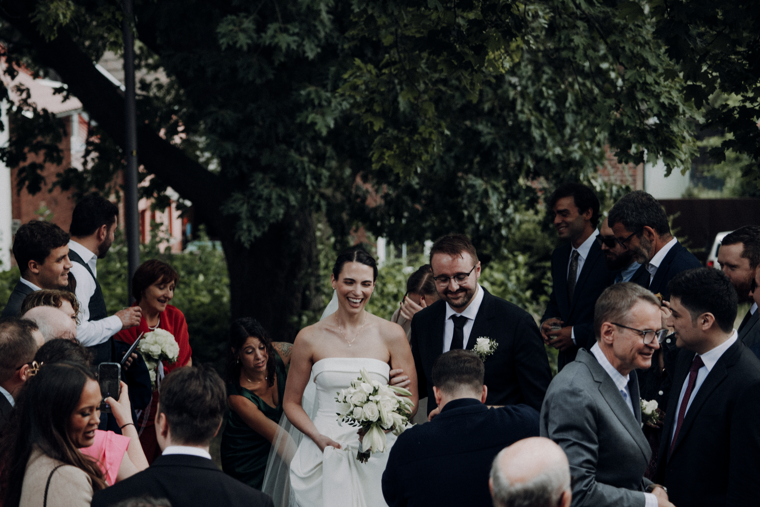 Wedding guests dance together during an outdoor reception celebration in a garden setting.