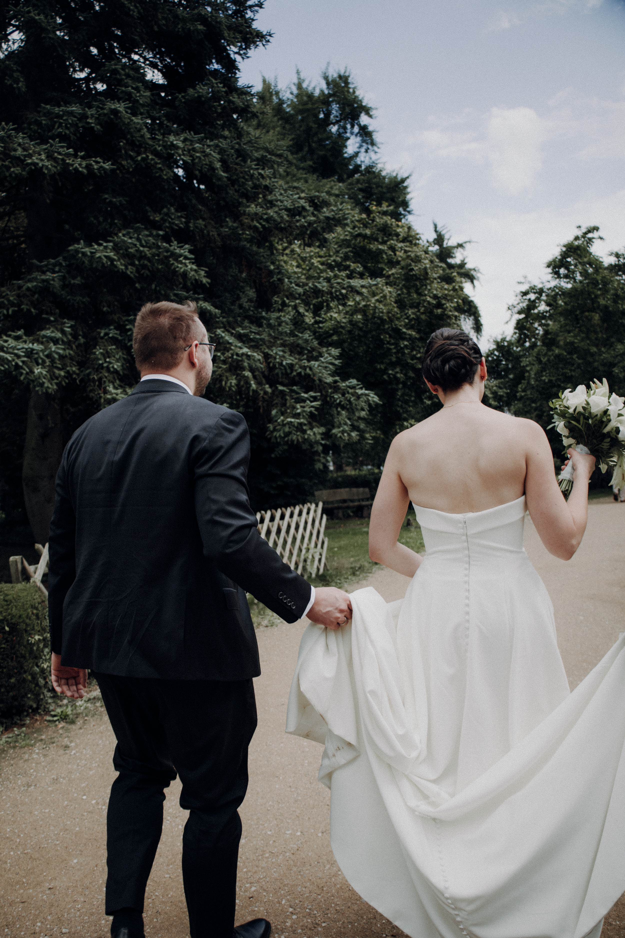A series of wedding photos showing a couple walking together on a garden path, with the bride's white dress flowing.