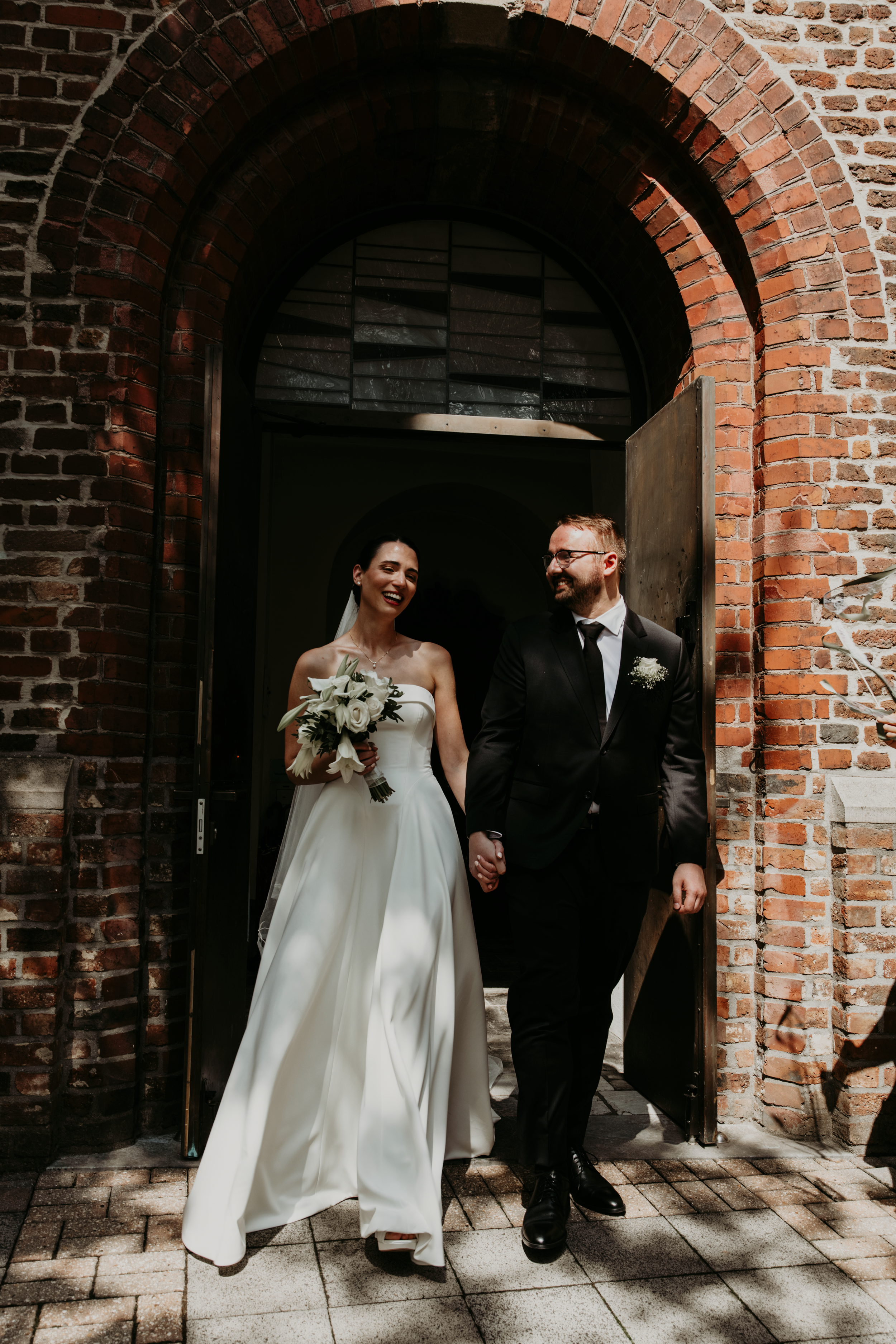 A wedding couple walks through a series of brick archways in a historic building, captured in a sequence of photos.