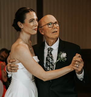 Bride and guest share a dance together at an indoor wedding reception.