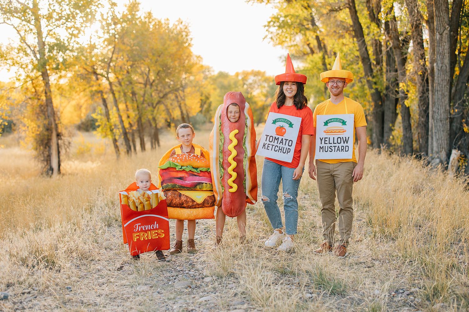 Family dressed up for halloween as fries, hamburger, hot dog, ketchup and mustard smiling at the camera.