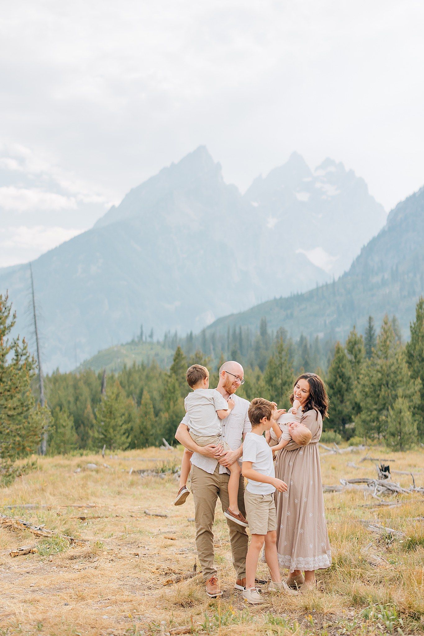 Family standing in a field in front of the Grand Tetons.