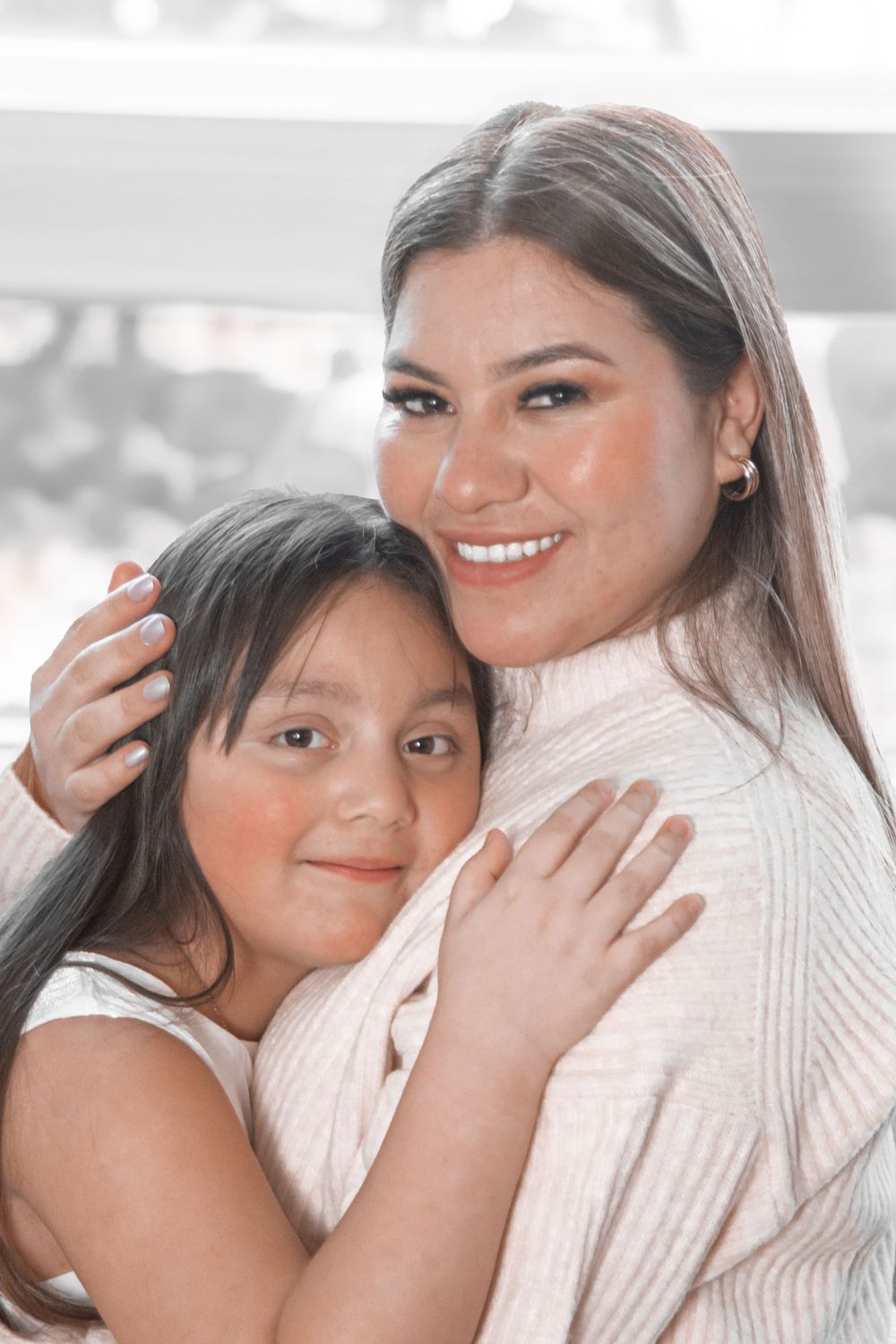 A tender moment captured between two people in white clothing sharing a warm embrace and genuine smiles.