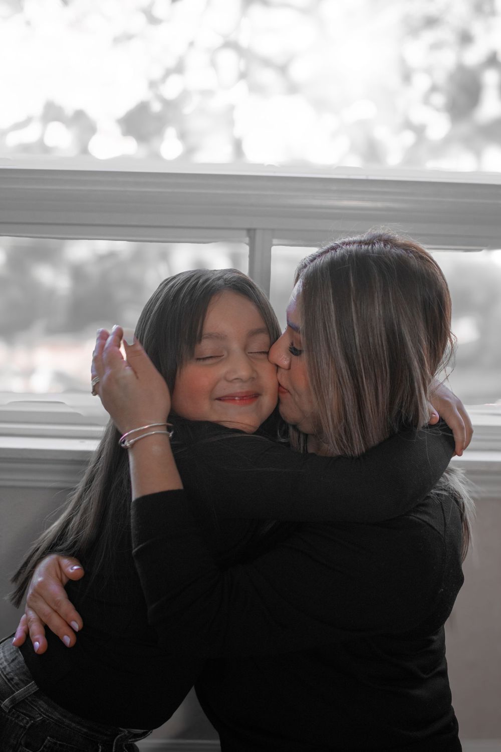 Two people share an emotional embrace in a series of black and white photographs showing closeness and affection.