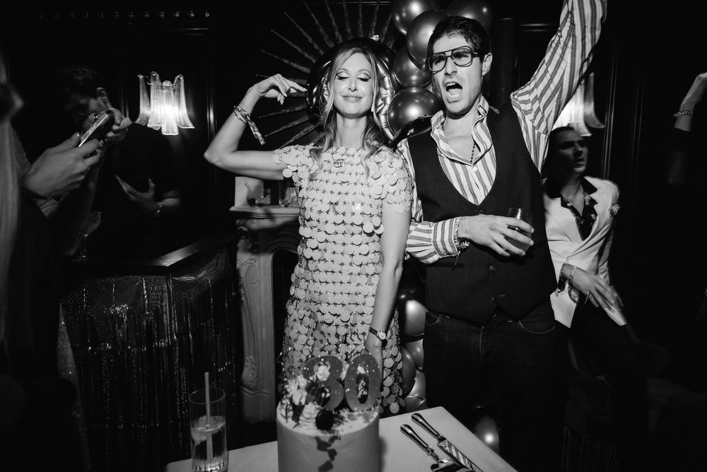 Black and white photo of people dancing and celebrating at a lively party or nightclub event.