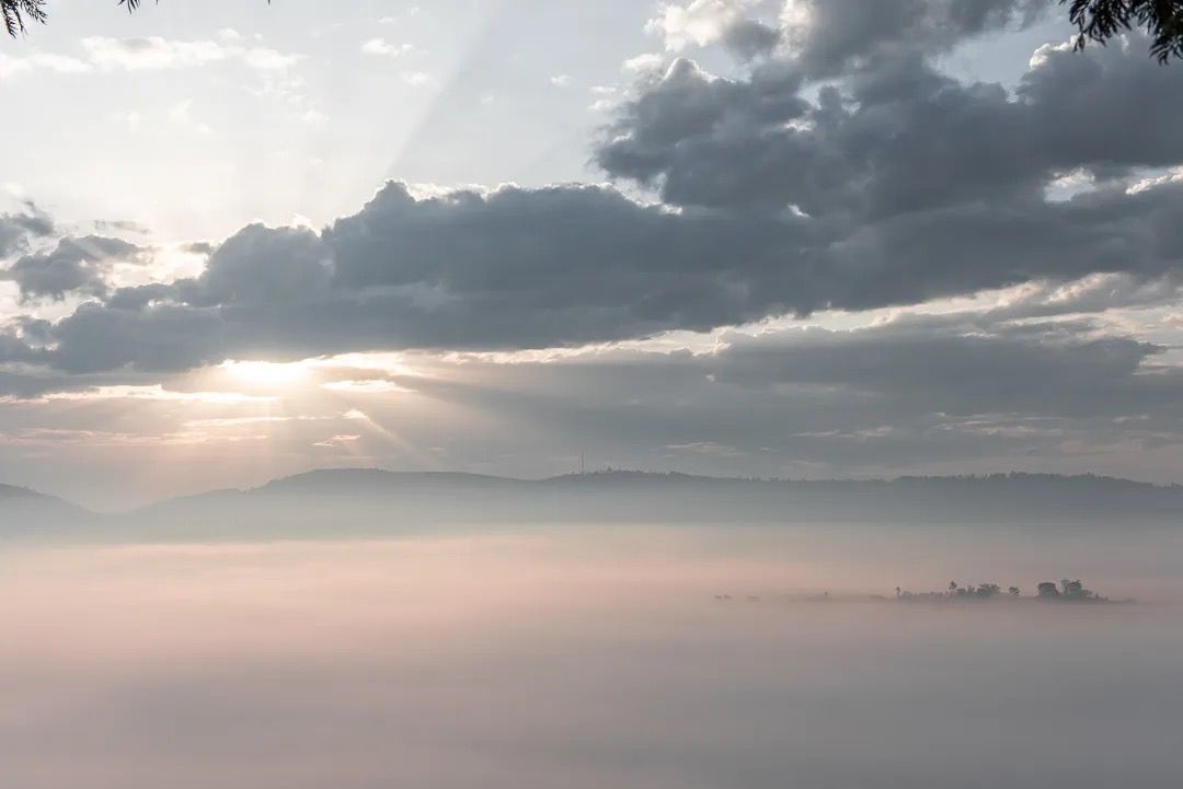 Sunlight breaks through dramatic clouds at sunrise, highlighting peaceful views, soft light and serene landscapes.