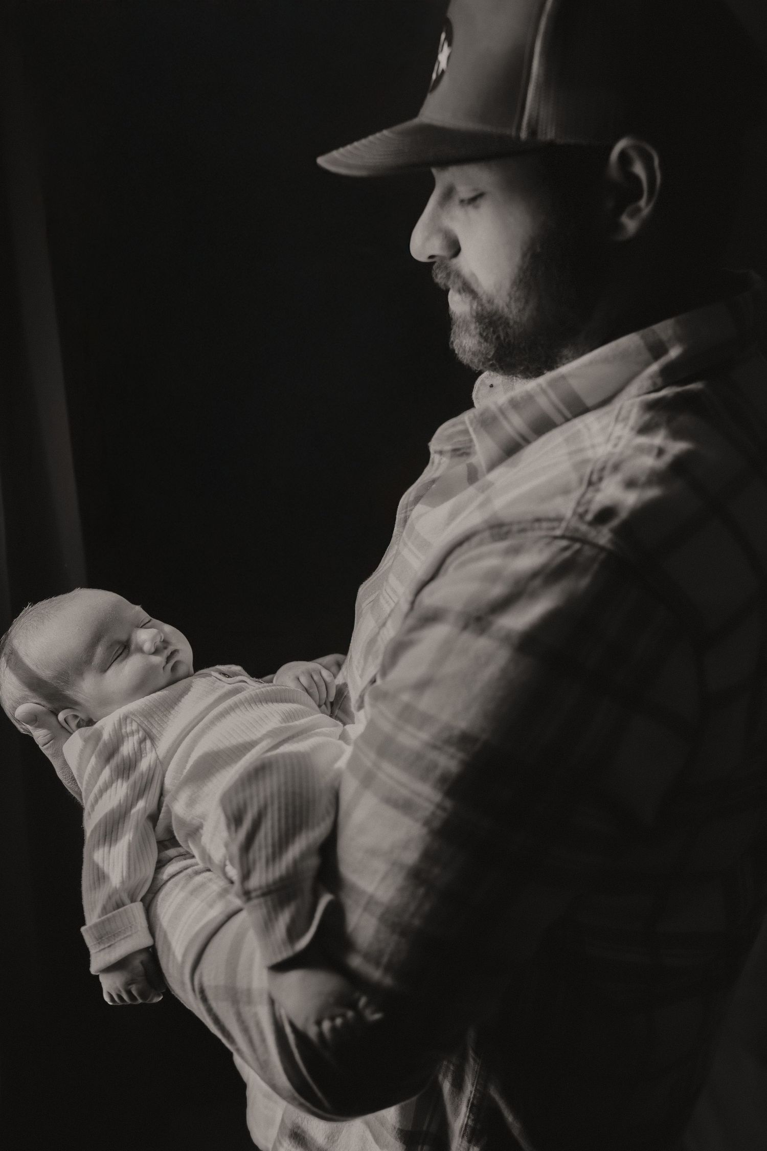 Black and white portrait series showing someone wearing a baseball cap in dramatic lighting.