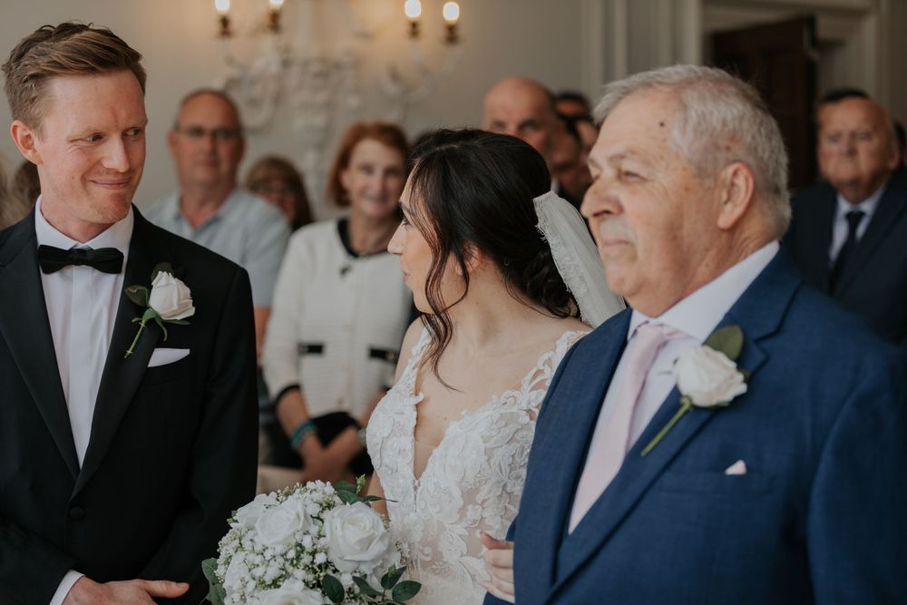 Bride and groom share a joyful moment with father of the bride at wedding altar.