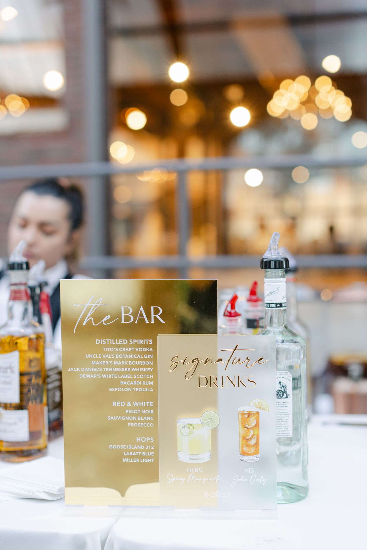 Elegant bar menu display with signature drinks text on gold signage and glowing bokeh lights in the background.