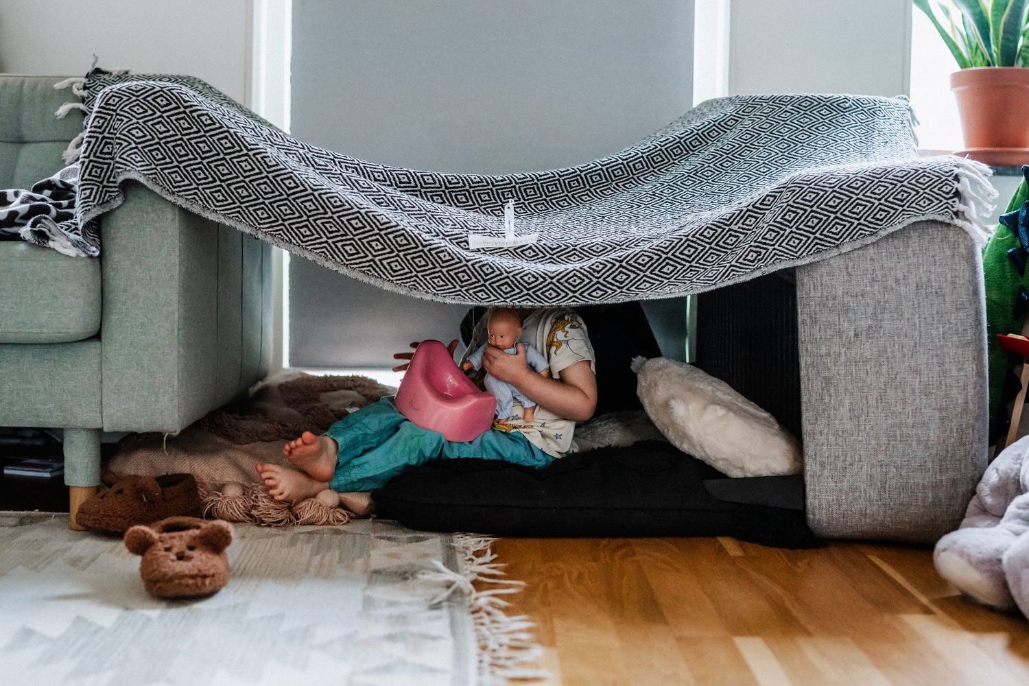 Ett barn sitter i en koja och huvudet skyms av kojans tak.