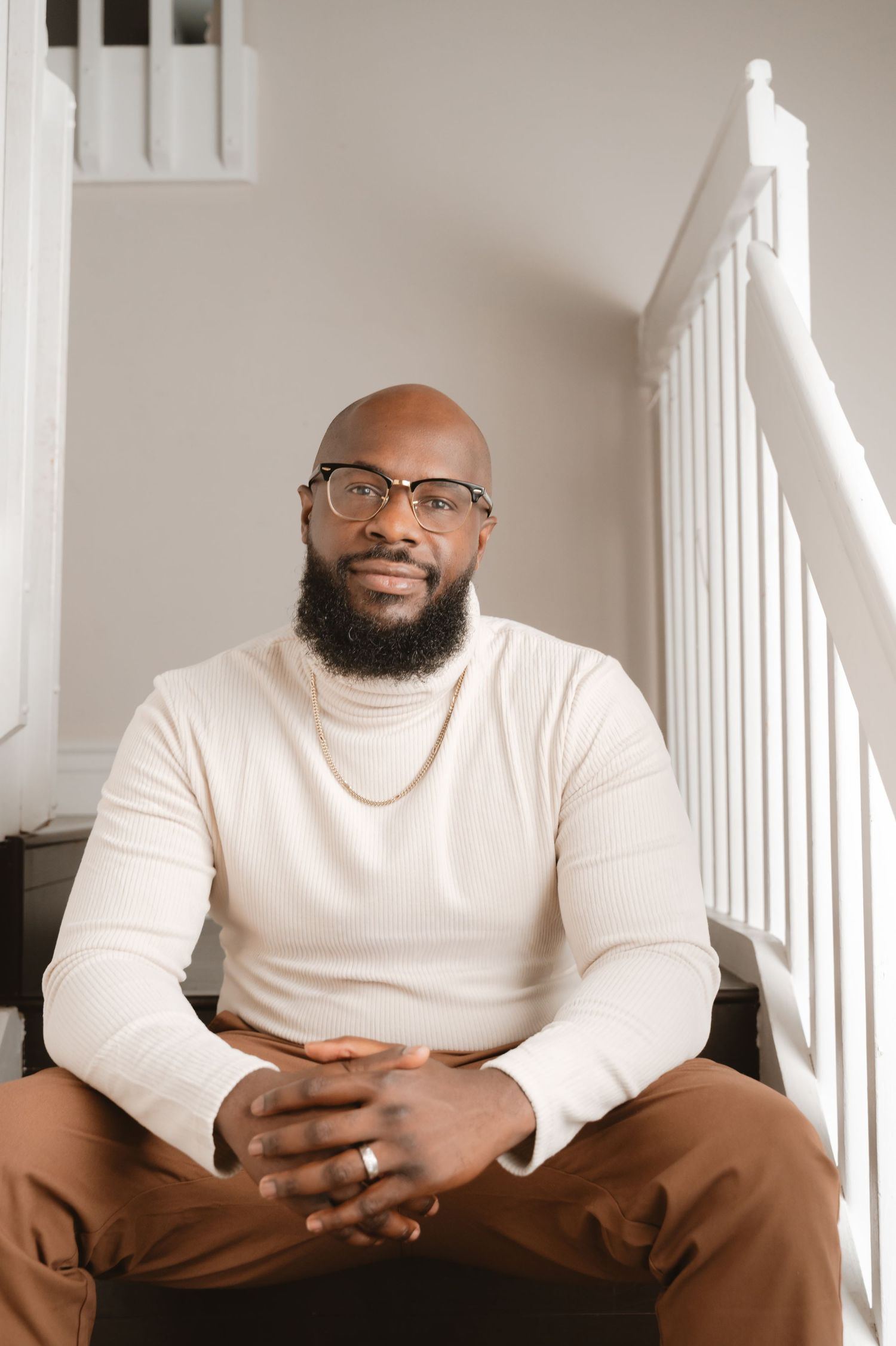 A person in a white shirt sits casually against a white wall in a series of three similar poses.