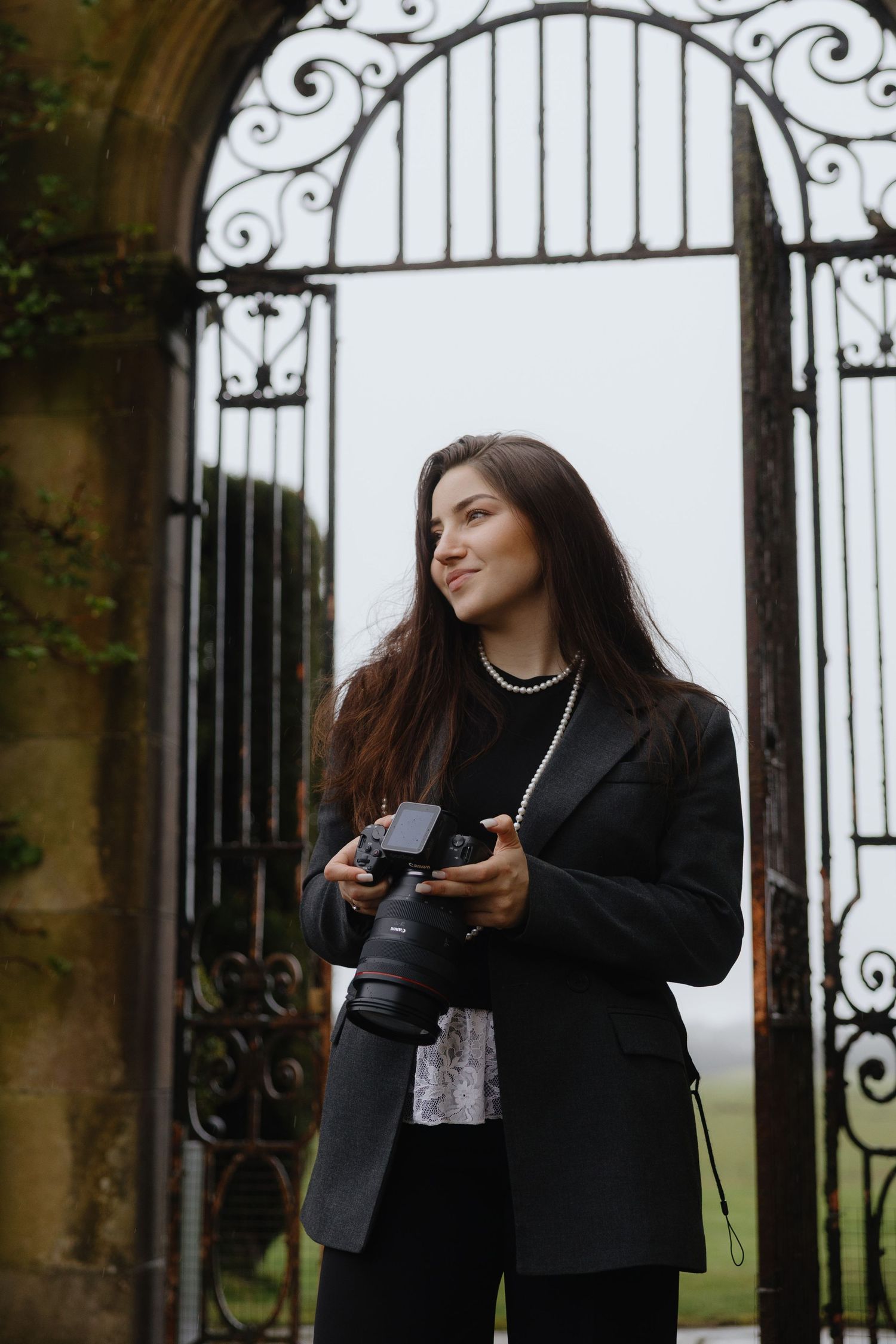 A person in a black coat and white sweater smiles while posing in a series of candid outdoor photos.