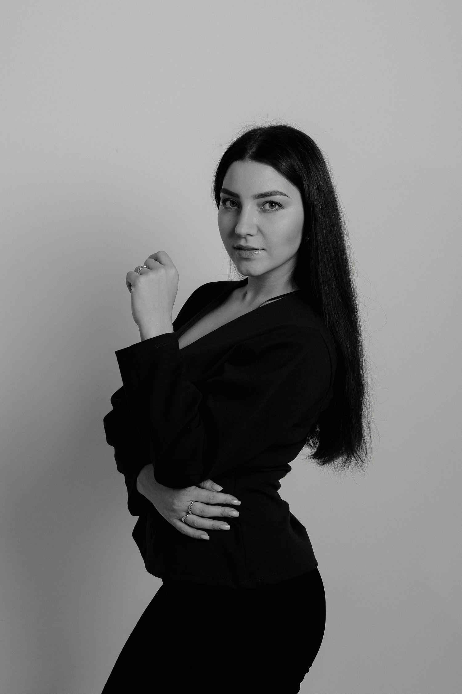 A person in a black coat and white sweater smiles while posing in a series of candid outdoor photos.