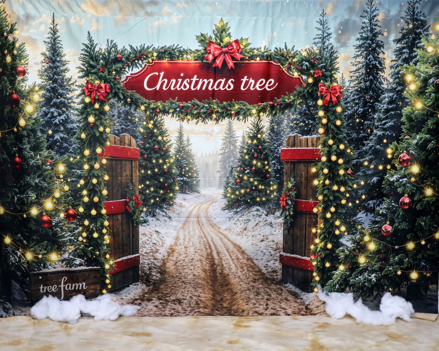 Christmas themed backdrop with lit trees and snowy path through decorated entrance gate.