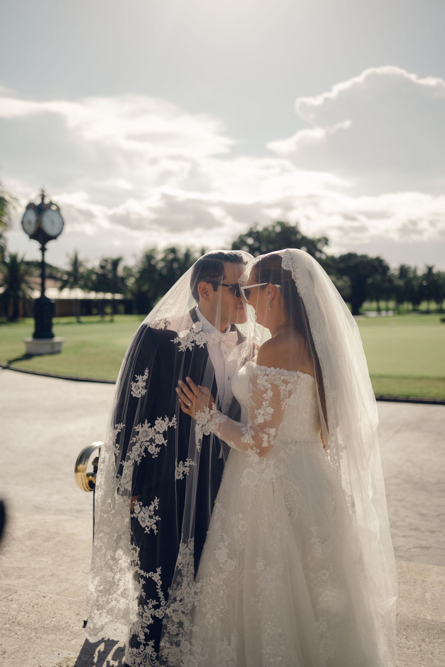 A romantic wedding photoshoot on a golf course with palm trees and cloudy skies in the background.