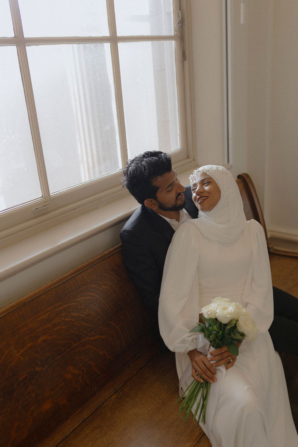 An intimate wedding photo session in a sunlit room with hardwood floors.