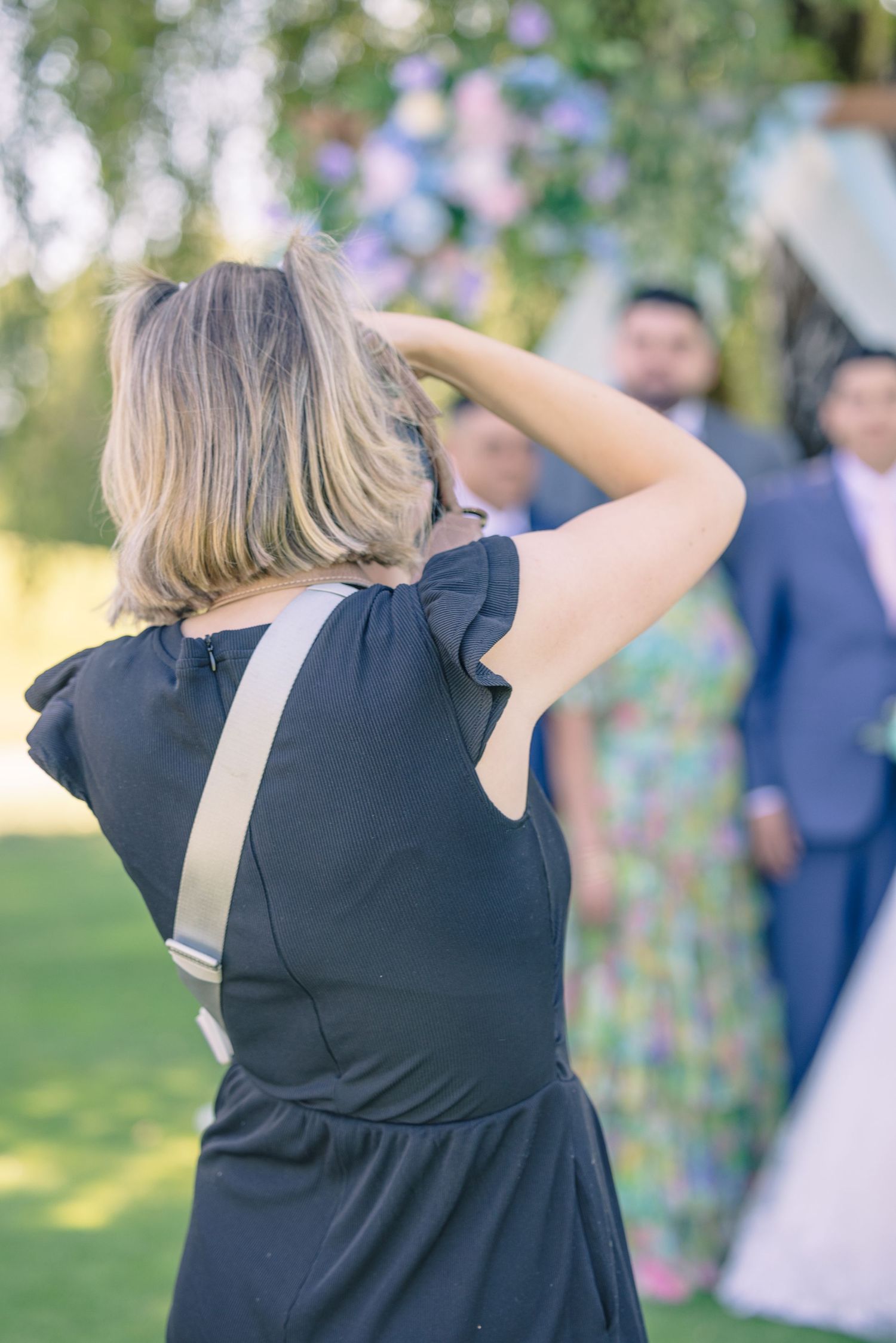 Photographer capturing shots at outdoor wedding with floral decorations in background.