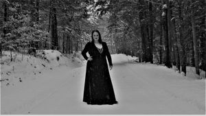 Snow-covered walking path through winter forest with evergreen trees.