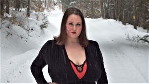 Person in black clothing standing on snowy forest path.