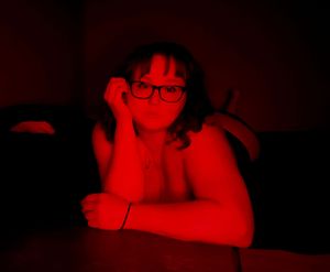 Dimly lit bedroom scene with red ambient lighting creating a moody atmosphere.