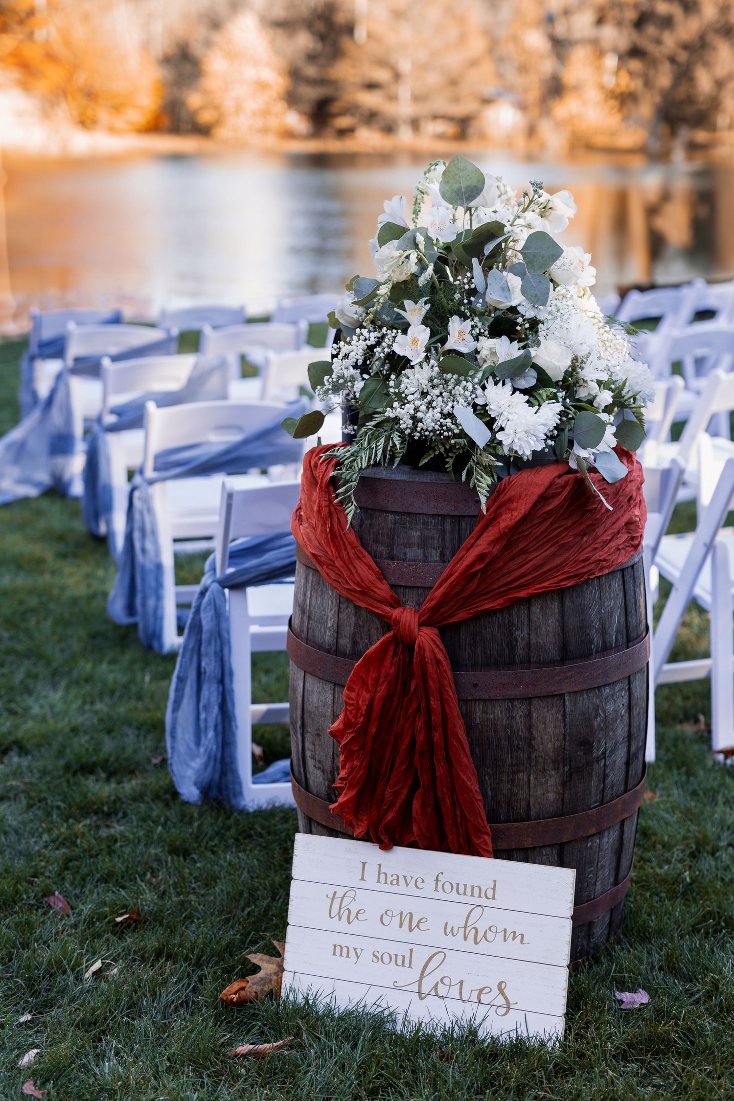 Rustic barn venue interior with wooden beams and circular chandelier creating warm ambiance.