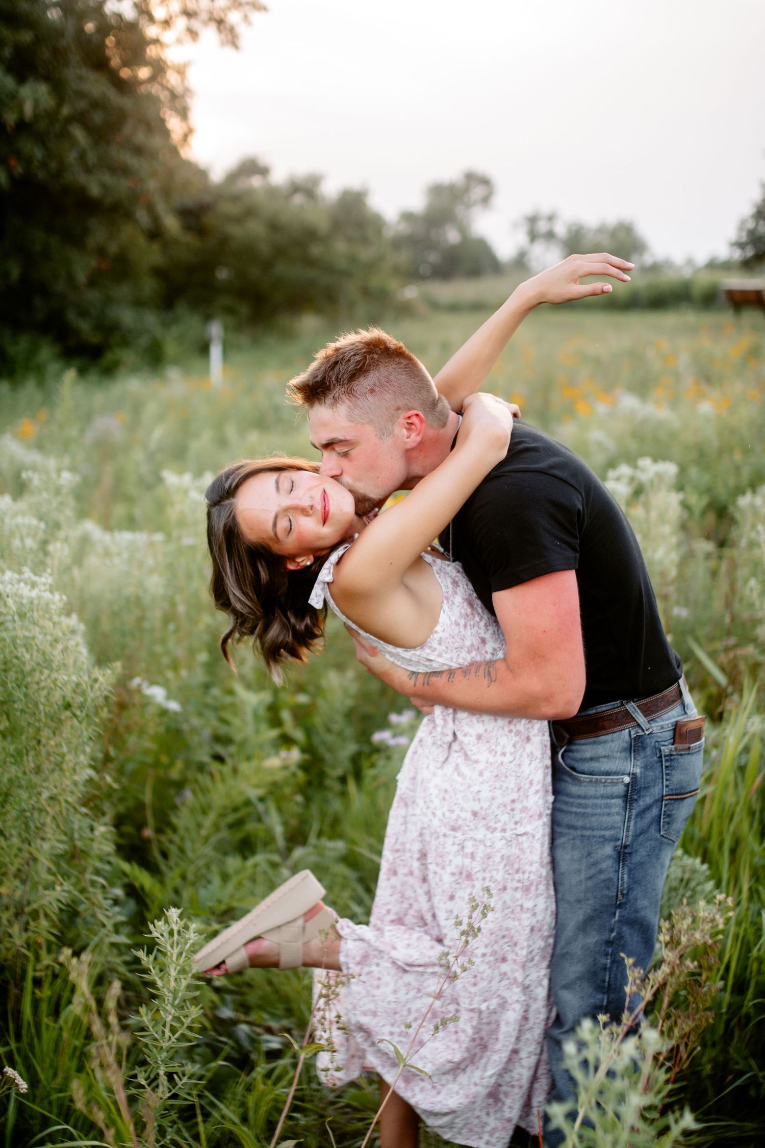 Couple sharing a kiss in a vibrant wildflower field, capturing a romantic and serene moment in nature.