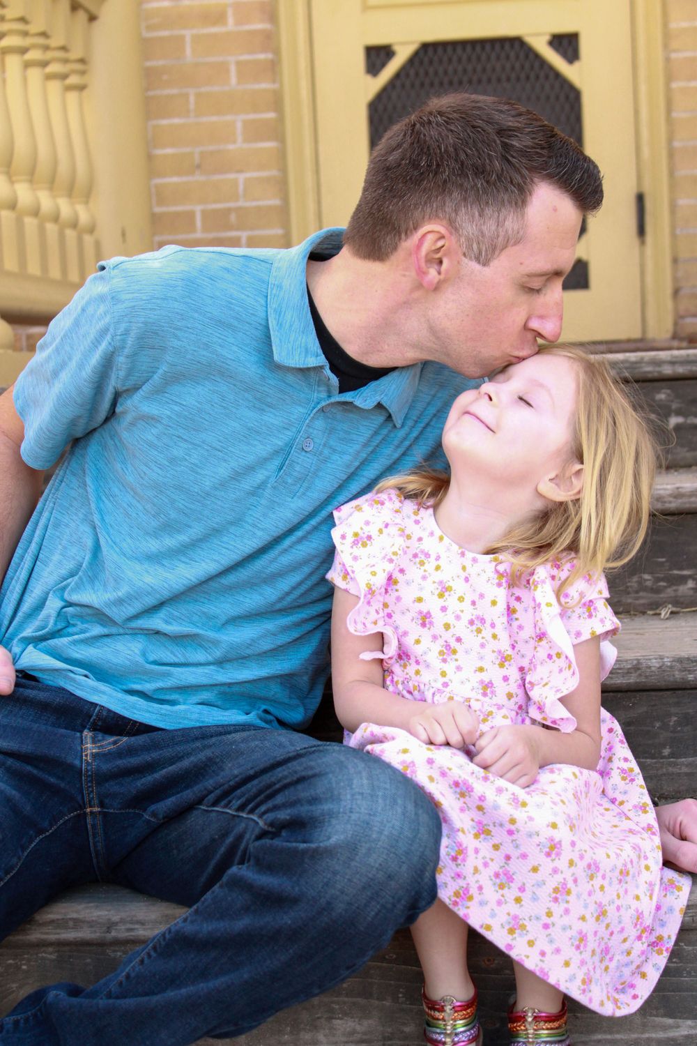 A touching moment captured on stone steps between parent and child in coordinated outfits.