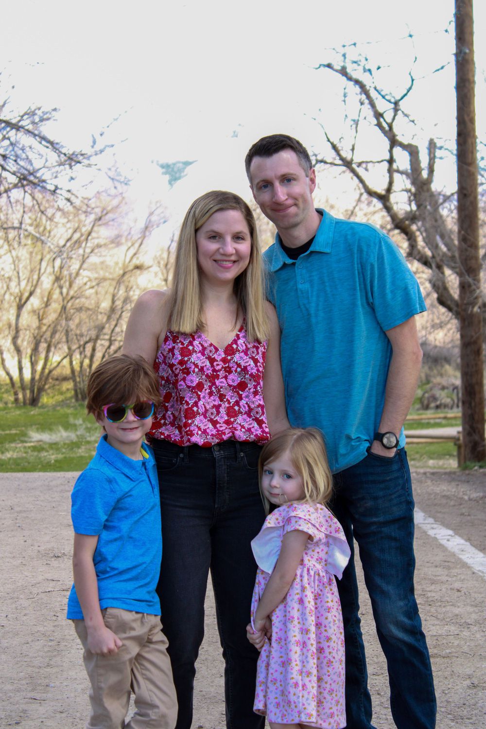 A family of four poses together outdoors on a spring day.