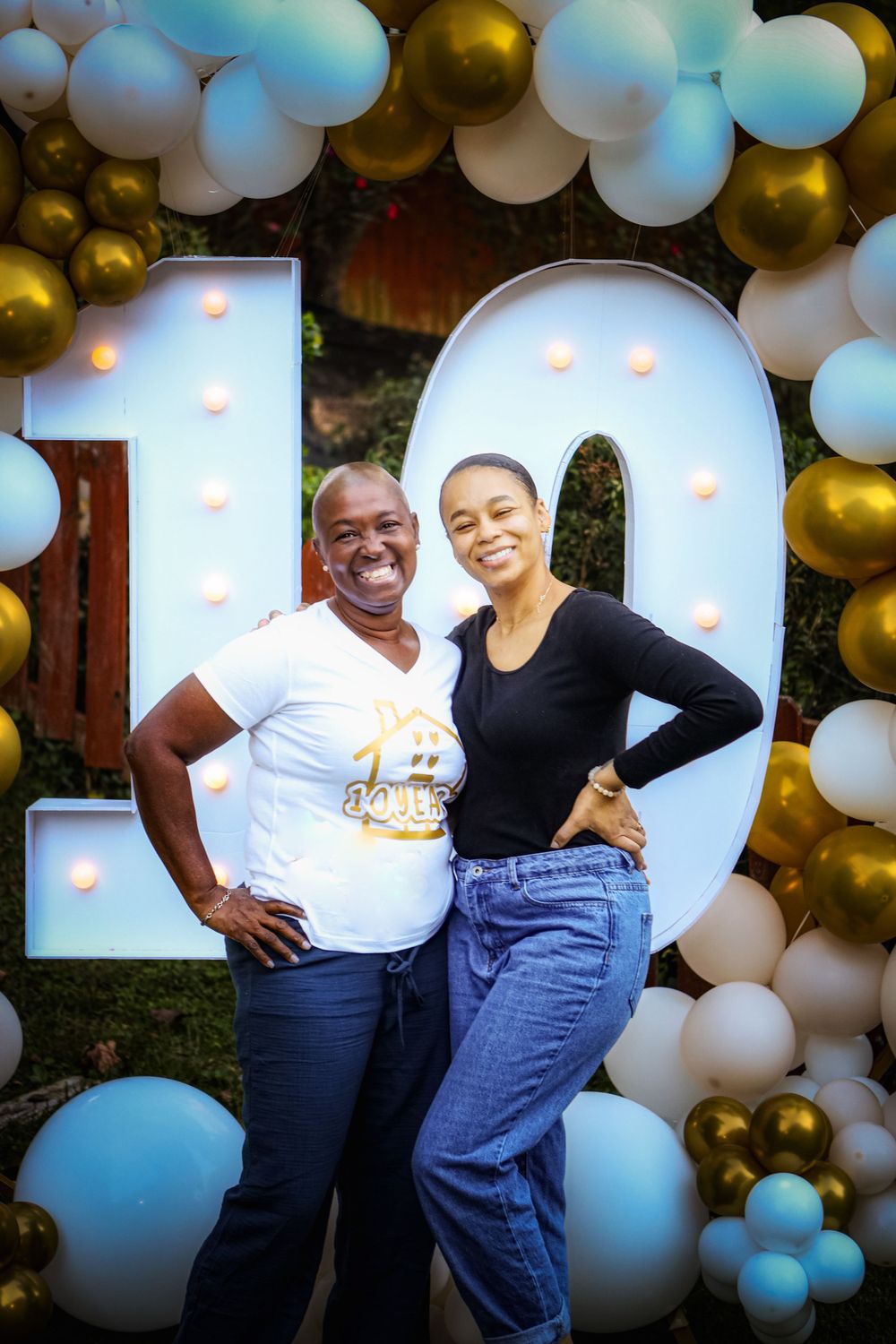 Two people posing in front of illuminated number 10 with balloon arch decoration.