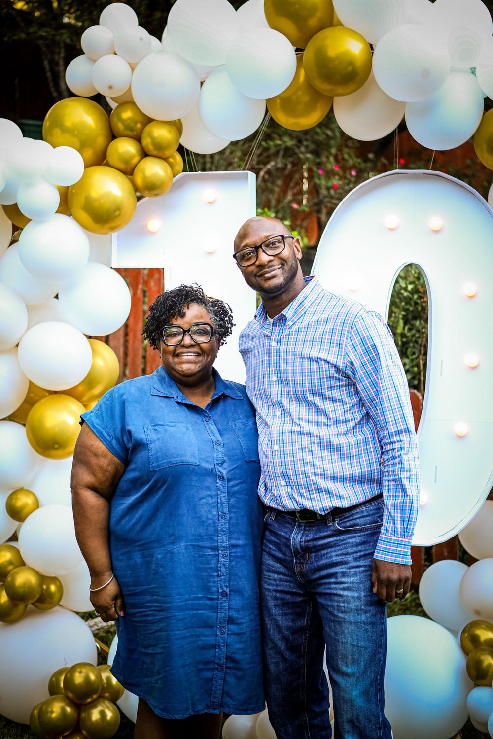 Celebration backdrop with white and gold balloon arch displaying number 10.