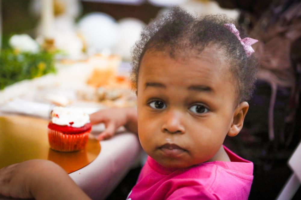 Child in pink shirt at outdoor celebration.