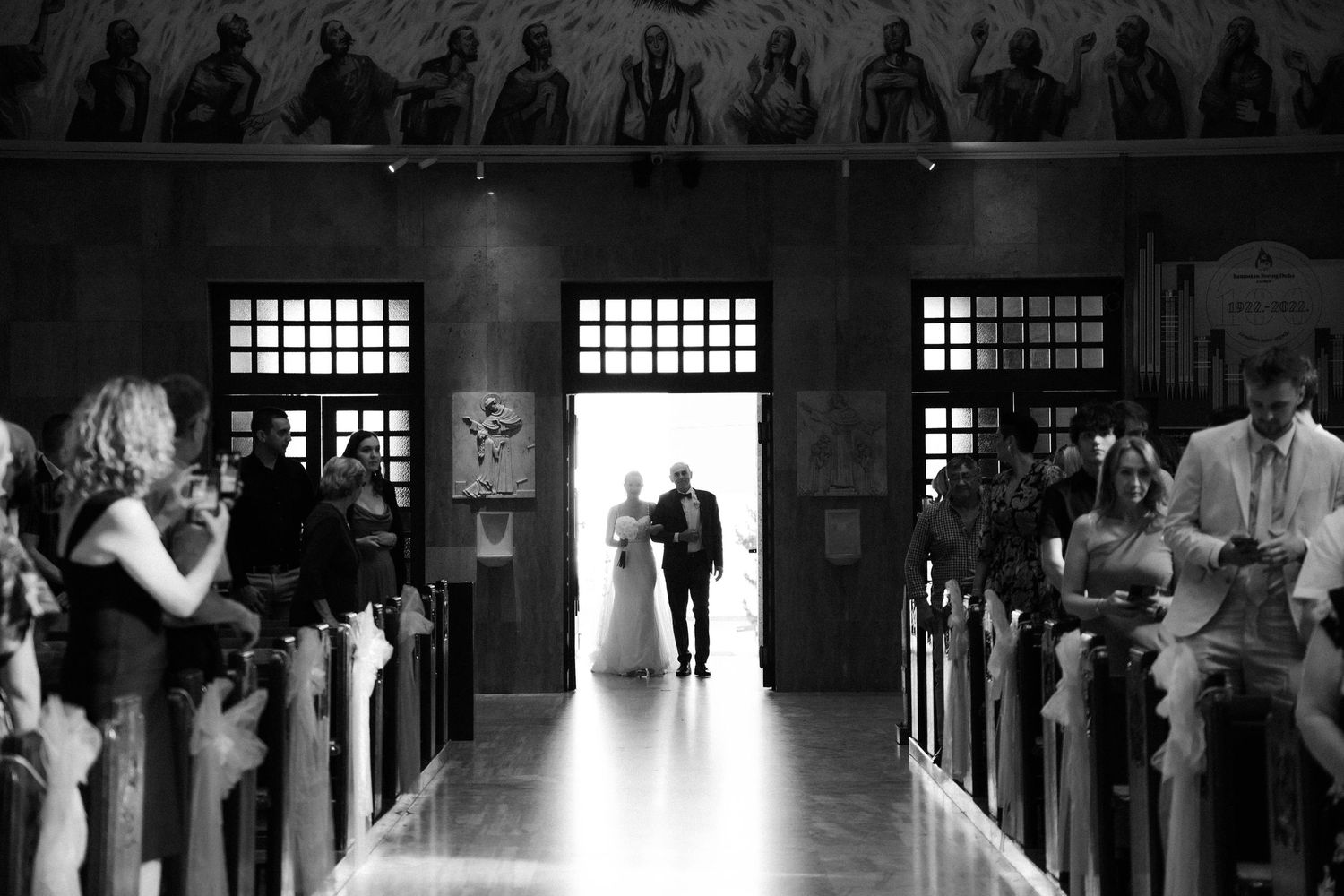 Dramatic black and white night photo of wedding party holding smoke flares on cobblestone path.