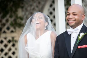 A joyful bride and groom share a happy candid moment during their outdoor wedding ceremony.