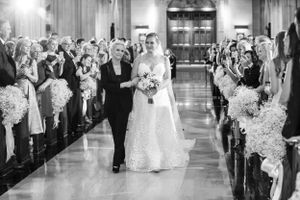 A black and white wedding photograph shows a traditional church ceremony processional with floral decorations lining the aisle.