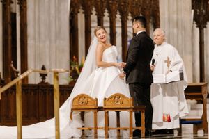 A traditional church wedding ceremony taking place at an ornate altar with gothic architectural details in the background.