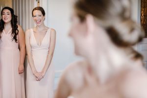 Bridesmaids in blush pink and cream dresses share joyful moments while getting ready for a wedding celebration.