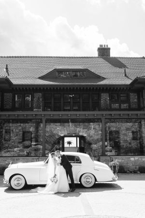 Classic white car parked in front of historic stone building with archway at a romantic wedding venue.