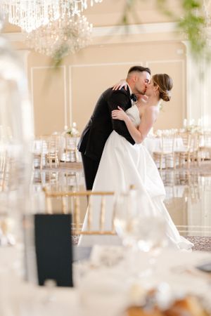 A romantic wedding moment captured in an elegant ballroom with crystal chandeliers and gold chiavari chairs.