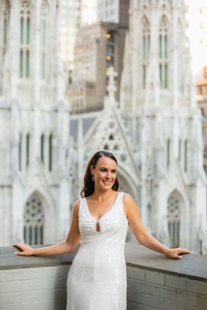 A person in an elegant white wedding dress poses in front of St. Patrick's Cathedral's Gothic architecture.