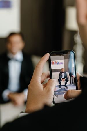 Someone taking a photo with smartphone of a person sitting in an office setting during a professional photoshoot.