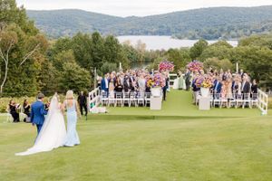 Outdoor wedding ceremony on a hilltop golf course overlooking mountains and lake on a sunny summer day.
