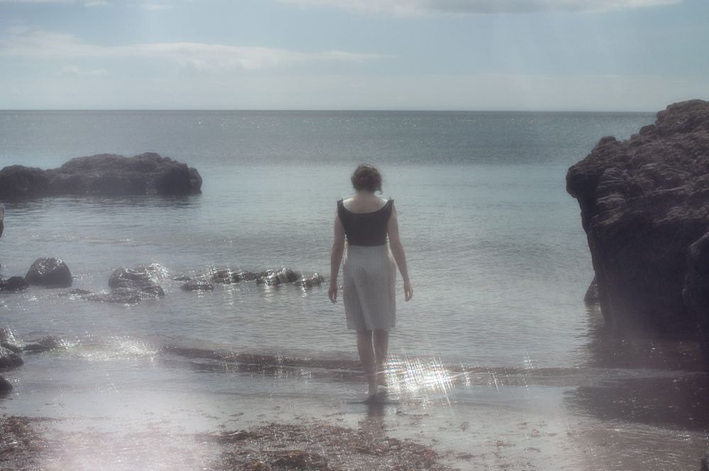 Misty artistic album cover photo of a woman walking into the sea